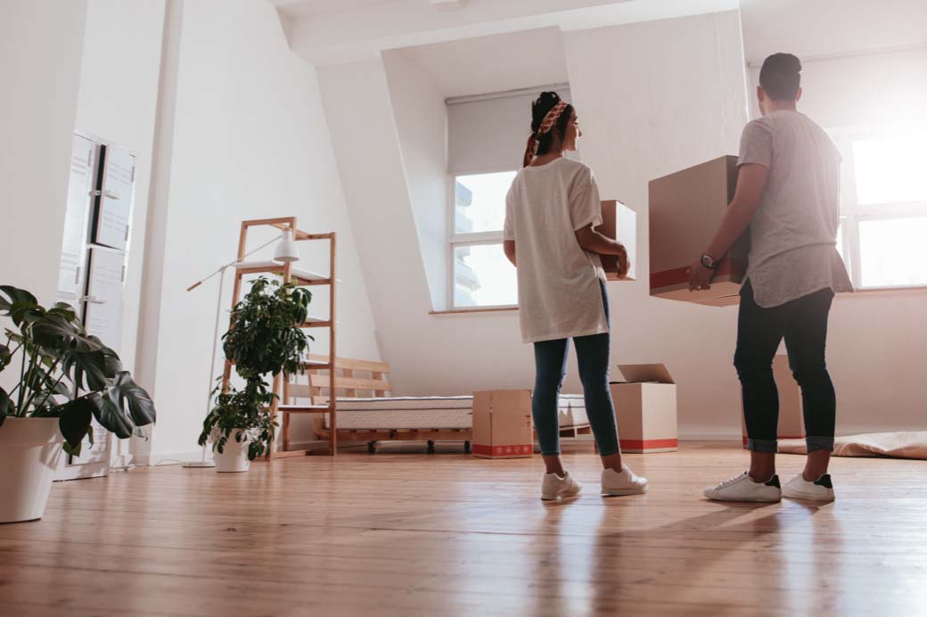 A couple holding boxes in a room.