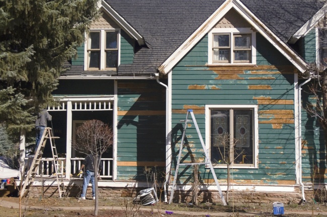 Older home needing repairs with ladders out front