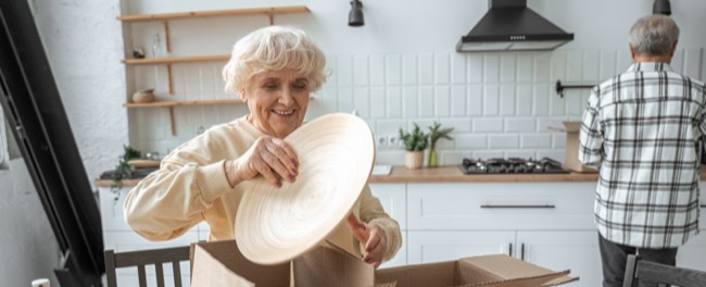 A senior couple packing dished in a kitchen.