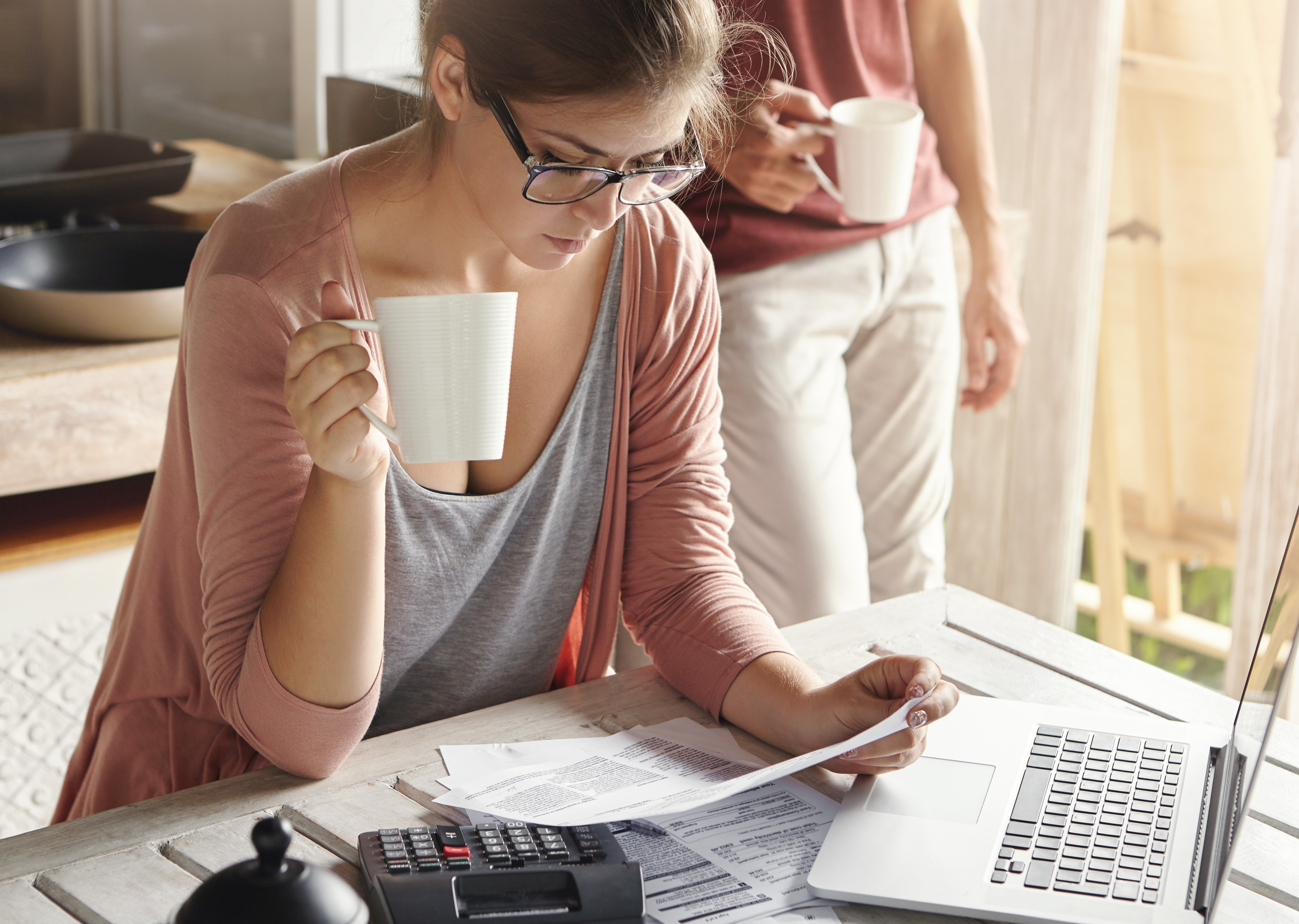 young-female-drinking-tea-studying-bill-her-hands-having-frustrated-look-while-managing-family-budget-doing-paperwork-sitting-kitchen-table-with-papers-calculator-laptop-computer.jpg?Revision=ZrM&Timestamp=3Wryfk